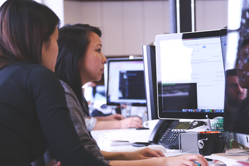 Leader training employee whilst sitting beside them at their PC